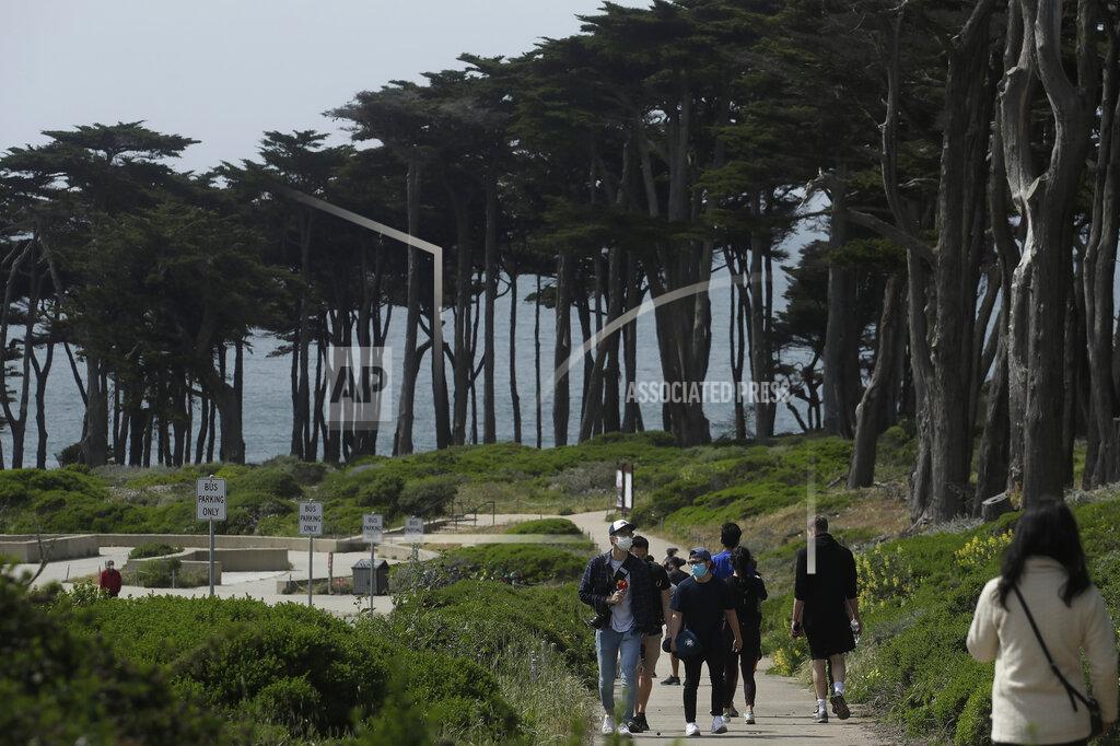 Jeff Chiu FILE - In this April 24, 2020, file photo people wear masks amid the coronavirus pandemic while walking on a path at Land's End in San Francisco. Lawmakers have reached bipartisan agreement on an election-year deal to double spending on a popular conservation program and devote nearly $2 billion a year to improve and maintain national parks. (AP Photo/Jeff Chiu, File)