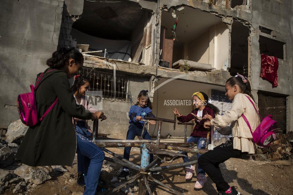 Khalil Hamra Young girls play in front of a destroyed house as they celebrate the first day of Eid al-Adha holiday in town of Beit Hanoun, northern Gaza Strip, Tuesday, July. 20, 2021. Eid al-Adha, or the festival of sacrifice, is celebrated by Muslims around the world to commemorate Prophet Ibrahim's test of faith. (AP Photo/Khalil Hamra)