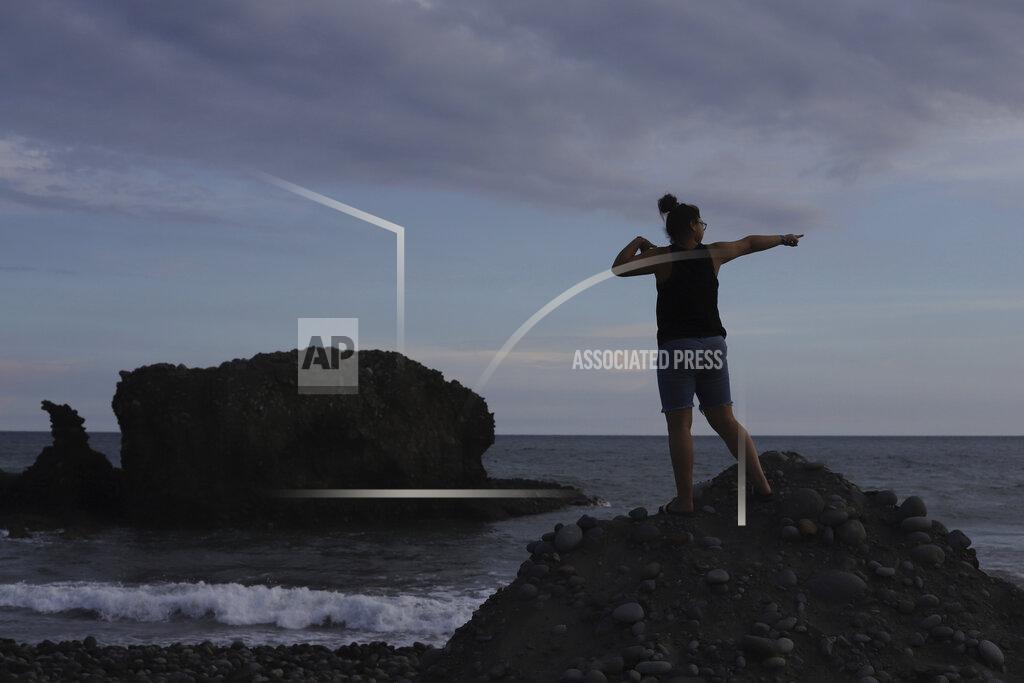 Salvador Melendez A tourist poses for a friend taking pictures along El Tunco Beach in Tamanique, El Salvador, Wednesday, June 9, 2021. In this beach community, a nongovernmental organization with the financial backing of an anonymous Bitcoin donor has been trying to create a small-scale cryptocurrency economy, and could serve as a showcase for the gains and struggles to introduce a phone-based cryptocurrency as the country embarks on a nationwide experiment after making Bitcoin legal tender this week. (AP Photo/Salvador Melendez)