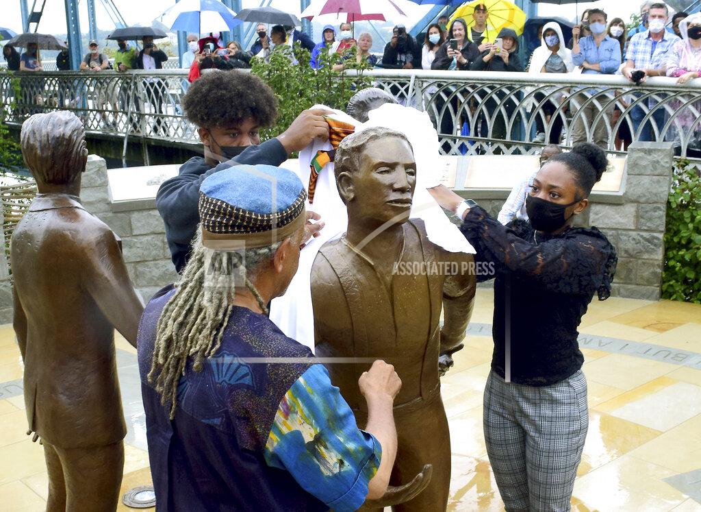Robin Rudd Howard School students Roy Miles and Trinity Smith help sculptor Jerome Meadows unveil his figure of Ed Johnson during the dedication ceremony of the Ed Johnson Memorial at the south side of the Walnut Street Bridge in Chattanooga, Tenn., on Sunday, Sept. 19, 2021. The two other figures are those of Noah Parden and Styles Hutchens, two African-American attorneys from Chattanooga, who provided a courageous and successful defense for Johnson, who on March 19, 1906, was mob-lynched from the second span of the Walnut Street Bridge. (Robin Rudd/Chattanooga Times Free Press via AP)