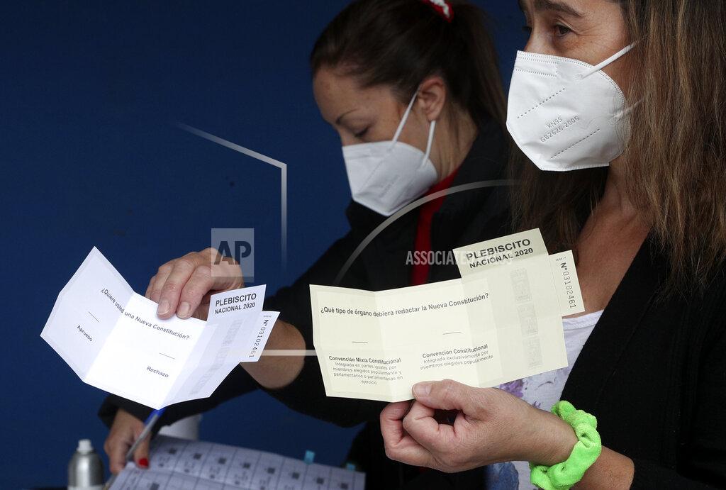 Esteban Felix Electoral officials hold ballots during a referendum to decide whether the country should replace its 40-year-old constitution, in Santiago, Chile, Sunday, Oct. 25, 2020. (AP Photo/Esteban Felix)