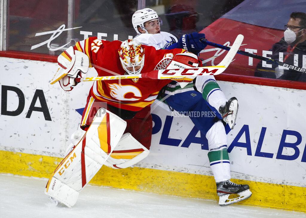 Jeff Mcintosh Vancouver Canucks' Nils Hoglander, right, is checked by Calgary Flames goalie Jacob Markstrom during the third period of an NHL hockey game Thursday, May 13, 2021, in Calgary, Alberta. (Jeff McIntosh/The Canadian Press via AP)