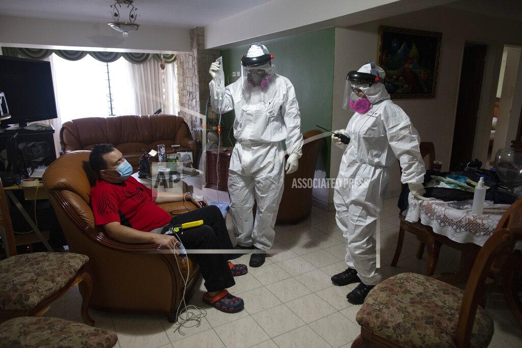Ariana Cubillos Angels of the Road volunteer paramedic Zully Rodiz, right, and Dr. Brayan Alfaro, measure the vital signs readings of a person suspected of having COVID-19, at his home in Caracas, Venezuela, Thursday, Feb. 11, 2021. The self-sufficient volunteer group, who seek their own funding and operate entirely independently of the government, are now prioritizing new coronavirus cases and offering free rides in their single ambulance to the hospital. (AP Photo/Ariana Cubillos)