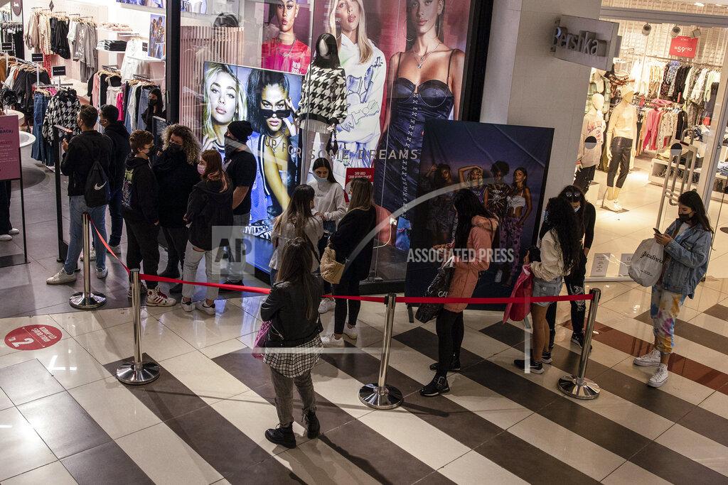 Consumers line up to enter a clothing store at a shopping center in the city of Beersheba, southern Israel, Sunday, Feb. 21, 2021. Israel lifted many of its coronavirus restrictions and started reopening its economy Sunday as the country's vaccination drive and third nationwide lockdown have started to bring down infections. (AP Photo/Tsafrir Abayov)