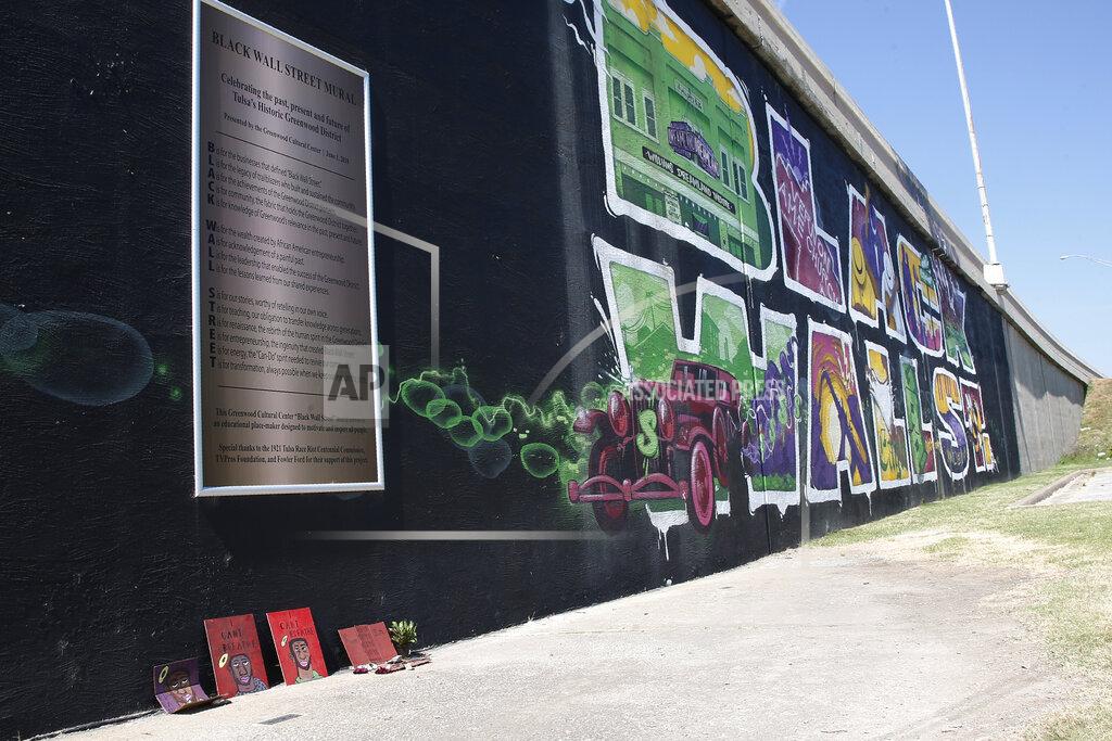 Sue Ogrocki A small memorial to George Floyd is pictured at the foot of a mural of Black Wall St. in Tulsa, Okla., Monday, June 15, 2020, on the other side of what's historically the city's white-black dividing line from where President Donald Trump will rally Saturday. (AP Photo/Sue Ogrocki)