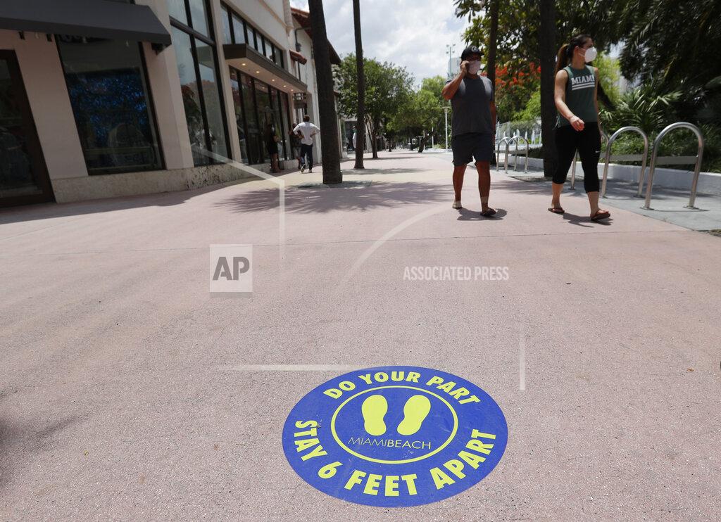 Shoppers wear masks to protect against the new coronavirus as they walk on Miami Beach, Florida's famed Lincoln Road, Wednesday, May 20, 2020. Miami, Miami Gardens, Hialeah and Miami Beach began phased openings of some shops Wednesday. (AP Photo/Wilfredo Lee)