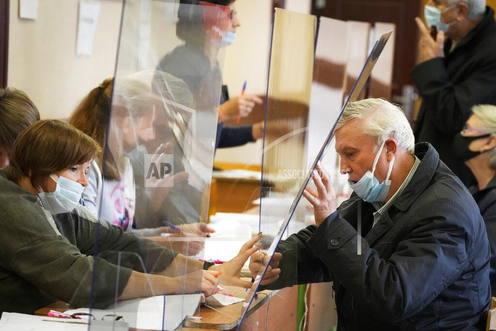 Dmitri Lovetsky A man is handed his ballots through a safety glass protecting from coronavirus infection during the State Duma, the Lower House of the Russian Parliament and local parliaments elections at a polling station in St. Petersburg, Russia, Friday, Sept. 17, 2021. Russia has begun three days of voting for a new parliament that is unlikely to change the country's political complexion. There's no expectation that United Russia, the party devoted to President Vladimir Putin, will lose its dominance in the State Duma. (AP Photo/Dmitri Lovetsky)