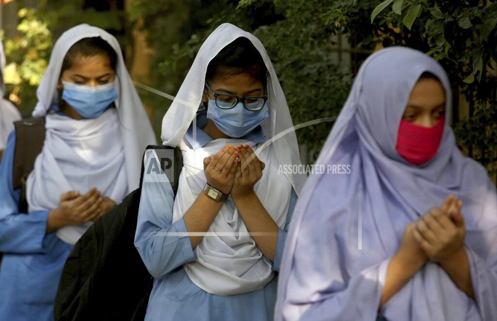 Fareed Khan Students wearing face masks to prevent the spread of the coronavirus as they pray upon their arrival at their school, in Karachi, Pakistan, Monday, Jan. 18, 2021. Pakistani authorities started to reopen schools in phases despite a steady increase in deaths and infections from the coronavirus, official said. (AP Photo/Fareed Khan)