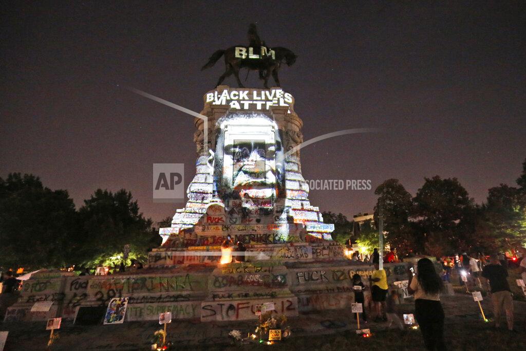 Steve Helber EDS NOTE: OBSCENITY - FILE - In this Monday, June 8, 2020 file photo, an image of George Floyd is projected onto the base of the statue of Confederate General Robert E. Lee on Monument Avenue in Richmond, Va. The U.S. has been dramatically disrupted in a matter of months, brought low by a global pandemic, Depression-era economic dislocation, and then, nationwide unrest over racial injustice. (AP Photo/Steve Helber)