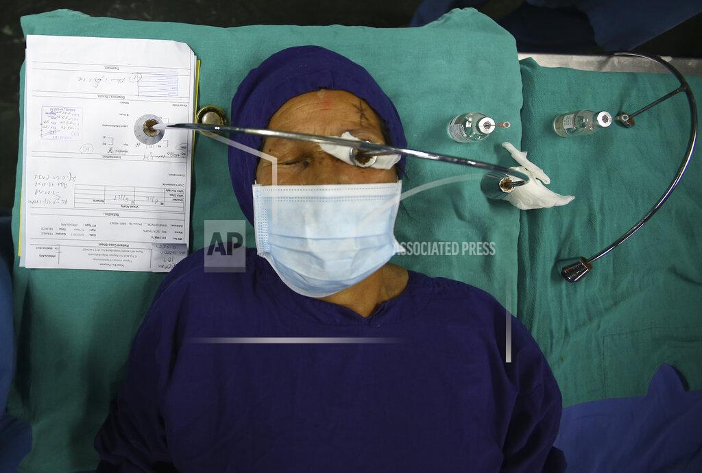Niranjan Shrestha A patient lies on a hospital bed after receiving anesthesia before cataract surgery at the Tilganga Eye Center in Kathmandu, Nepal, March 26, 2021. Nepal’s “God of Sight” eye doctor renowned for his innovative and inexpensive cataract surgery for the poor is taking his work beyond the Himalayan mountains to other parts of the world so there is no more unnecessary blindness in the world. Dr. Sanduk Ruit, who has won many awards for his work and performed some 130,000 cataract surgery in the past three decades, is aiming to expand his work beyond the borders of his home country and the region to go globally. (AP Photo/Niranjan Shrestha)