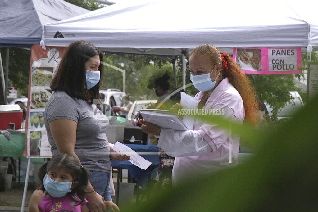 Federica Narancio A "promotora" (health promoter) from CASA, a Hispanic advocacy group, tries to enroll Latinos as volunteers to test a potential COVID-19 vaccine, at a farmers market in Takoma Park, Md., on Sept. 9, 2020. Minority enrollment in studies of two shots has inched up in recent weeks, but even more is needed this fall as additional vaccine testing gets underway over the next two months. (AP Photo/Federica Narancio)