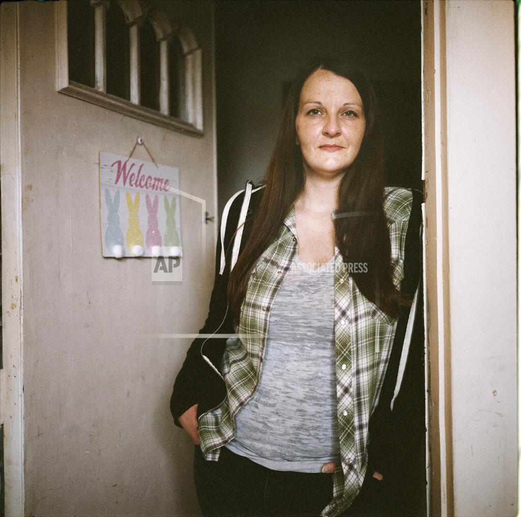 David Goldman In this photo made with a medium format film camera, Sarah Kelly, 37, stands in the doorway of her home in Guyandotte, W.Va., Wednesday, March 17, 2021. After struggling with opioid addiction most of her life, Kelly white-knuckled her way through the pandemic. Then she navigated courts to get custody of her kids back after more than two years apart. Kelly's younger sister died from a heart infection from injection drug use in 2017, and her own addiction spiraled as she tried to numb herself from guilt and despair. "I knew there was this version of me still in there somewhere, and I knew that if I woke up every day and really decided to stay sober, I could get to be her again," she said. "I could look in the mirror and be proud of who I was, and my children could be proud of me." They live together now in a little house on the outskirts of town. (AP Photo/David Goldman)