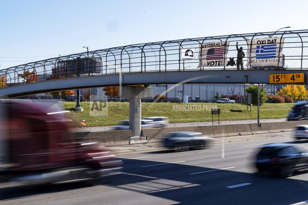 David Goldman An Iraq and Afghanistan war veteran, who did not give his name, stands on a highway overpass with signs encouraging motorists to vote in Hamtramck, Mich., Wed, Oct. 28, 2020. Early voting numbers, nearly 90 million by Saturday morning, suggest 2020 will shatter voter turn-out records. Trump has alleged without evidence that wide-spread absentee voting will lead to fraud. (AP Photo/David Goldman)