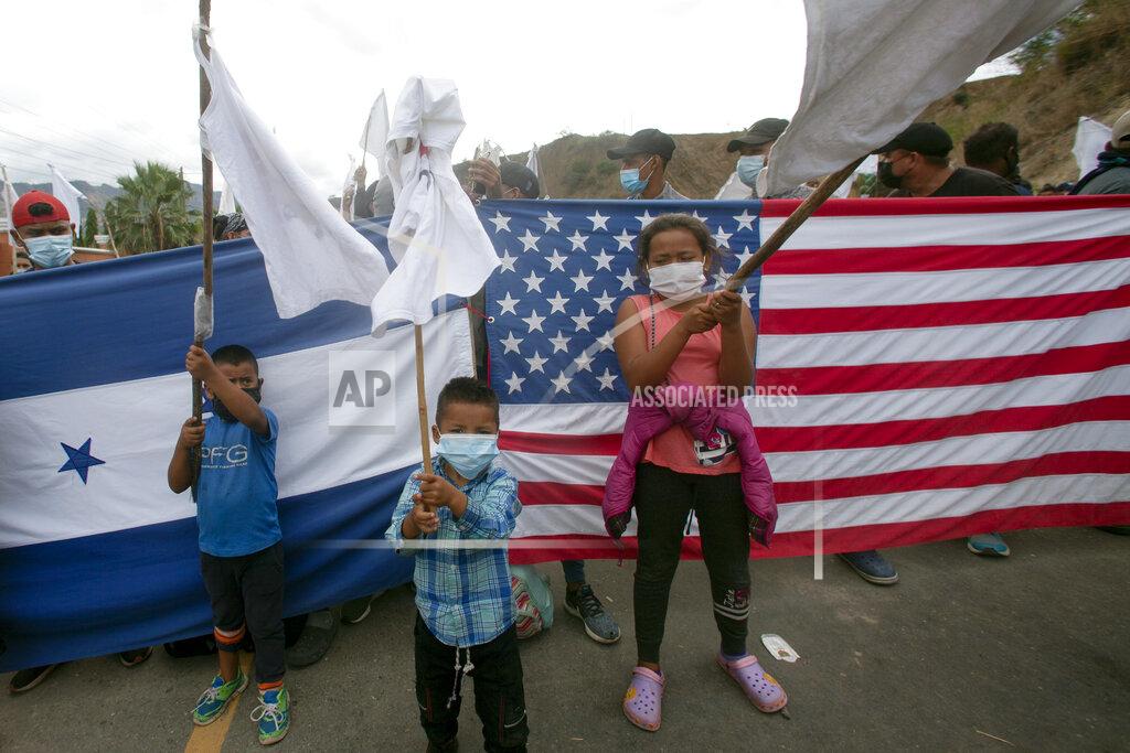 Sandra Sebastian Honduran migrant children raise white flags in front of a Honduran and American flag, as they are blocked by Guatemalan soldiers and police from advancing toward the U.S.-Mexico border, on the highway in Vado Hondo, Guatemala, Monday, Jan. 18, 2021. Some migrants have expressed hope about a friendlier reception from the new U.S. administration. (AP Photo/Sandra Sebastian)