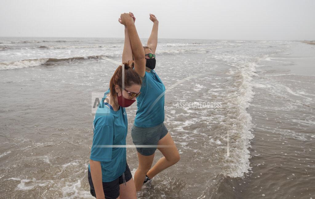 David Grunfeld Audubon's Coastal Wildlife Network Rescue, and Rehab Coordinator Gabriella Harlamert, left, and co-worker Nicole Kieda celebrate the rehabilitation victory after releasing the 13th Kemp's Ridley sea turtle, the last turtle for the day, on the beach in Grand Isle Monday, March 15, 2021. Audubon's Coastal Wildlife Network rehabilitated 19 cold-stunned Kemp's Ridley sea turtles after a deep arctic airmass along the New England coast in November 2020 threatened to kill the turtles. (David Grunfeld/The Advocate via AP)