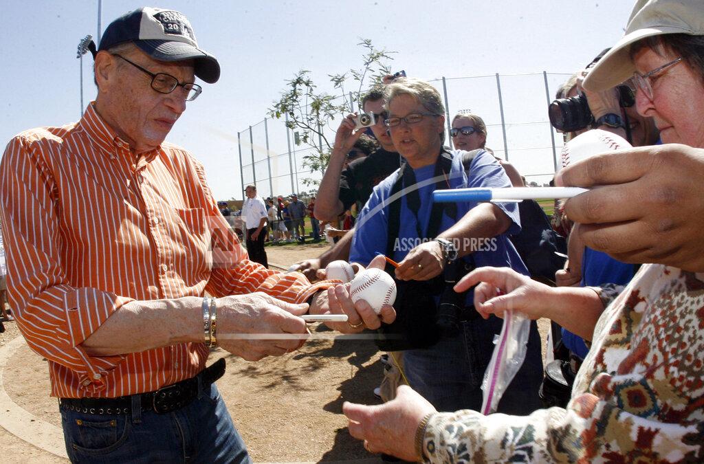 Keith Birmingham Los Angeles Dodger fan Larry King, left, signs autographs before a baseball game between the Arizona Diamondbacks and the Los Angeles Dodgers at Camelback Ranch Glendale Stadium on Tuesday March 10. 2009, in Phoenix. King, the suspenders-sporting everyman whose broadcast interviews with world leaders, movie stars and ordinary Joes helped define American conversation for a half-century, died Saturday, Jan. 23, 2021, at age 87. (Keith Birmingham/The Orange County Register/SCNG via AP)