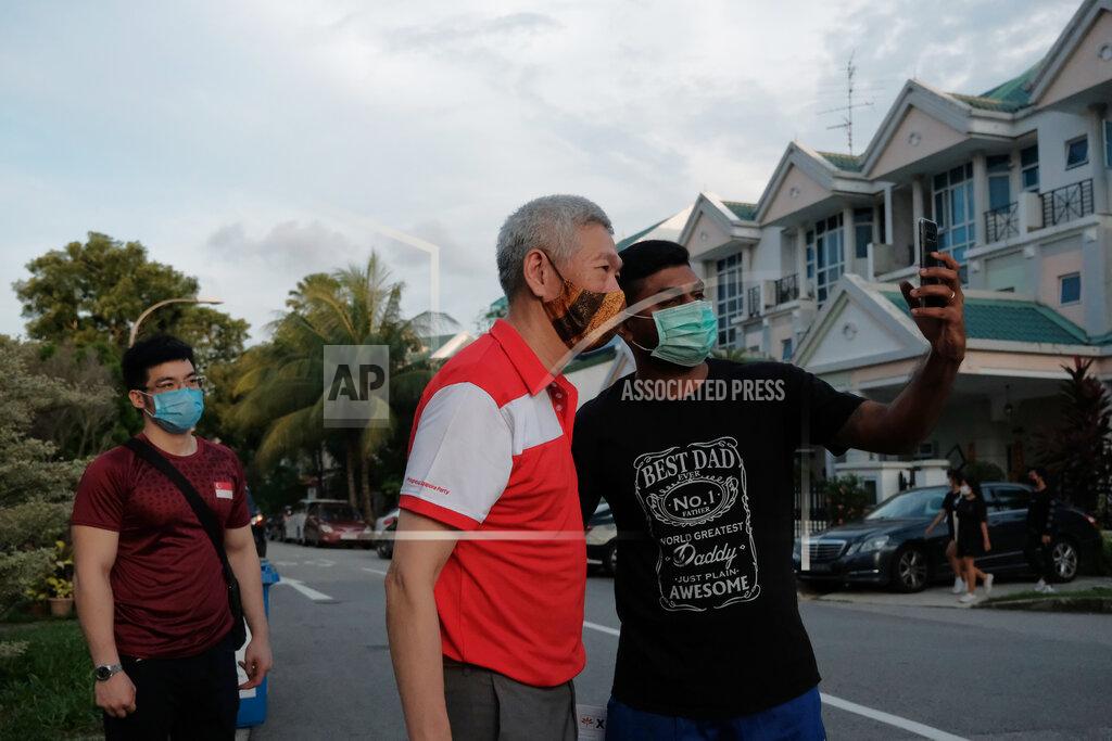 Ee Ming Toh Lee Hsien Yang, center, the estranged brother of Singapore Prime Minister Lee Hsien Loong, wears a face mask while posing for a selfie with a supporter at a private estate in Jurong West during a walkabout campaign for the opposition Progress Singapore Party July 8, 2020, in Singapore. Singaporeans go to the polls on July 10 in Southeast Asia's first election since the coronavirus pandemic began, with the health crisis and an economic recession expected to bolster Prime Minister Lee's party and extend its unbroken rule. (AP Photo/Ee Ming Toh)
