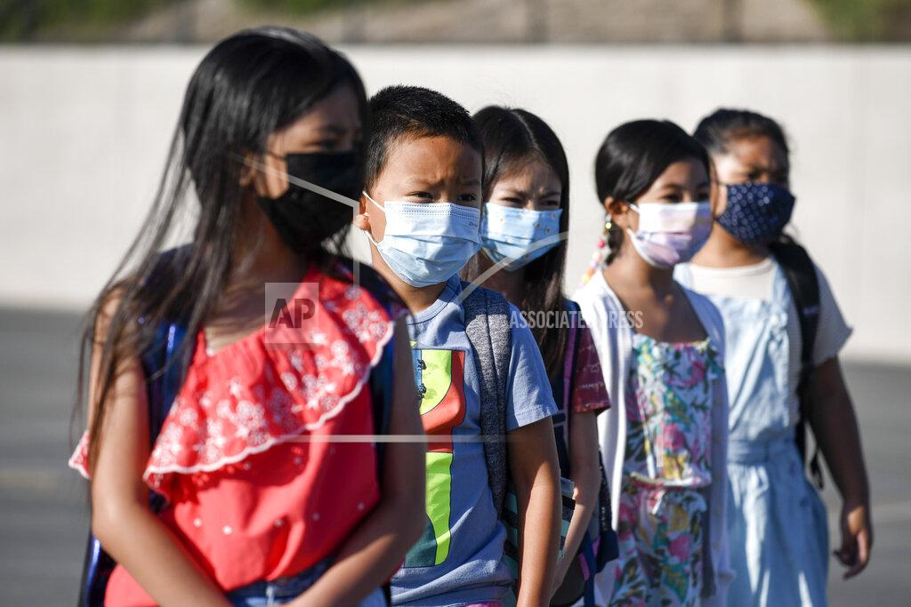 Denis Poroy Masked students wait to be taken to their classrooms at Enrique S. Camarena Elementary School, Wednesday, July 21, 2021, in Chula Vista, Calif. The school is among the first in the state to start the 2021-22 school year with full-day, in-person learning. (AP Photo/Denis Poroy)