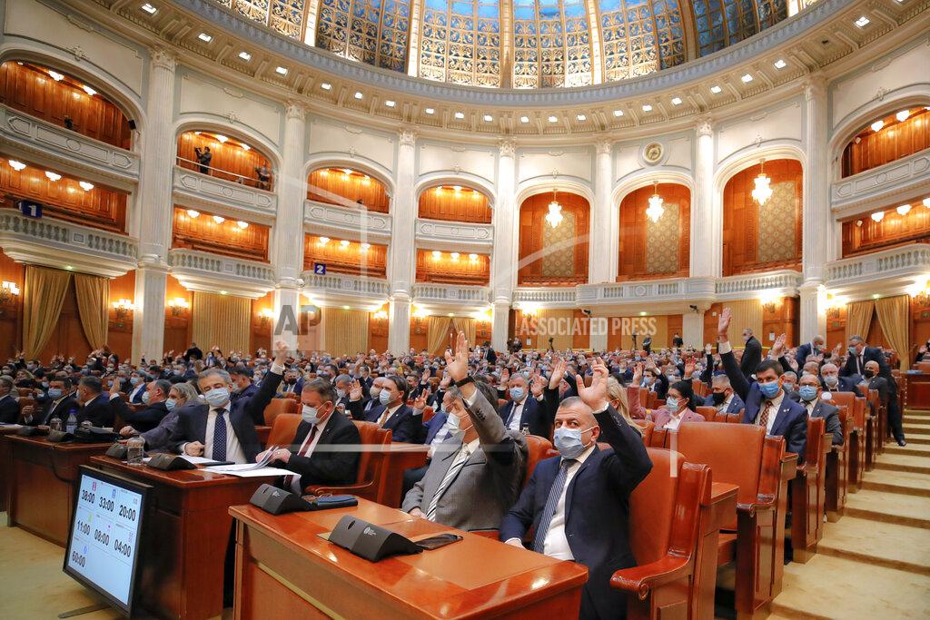 Vadim Ghirda Members of parliament raise their hands while voting on procedural issues before a session called to vote on the government team of Romanian prime minister-designate Florin Citu in Bucharest, Romania, Wednesday, Dec. 23, 2020. Romania's president Klaus Iohannis appointed on Tuesday, the outgoing finance minister as prime minister-designate after three pro-Western center-right groups joined forces to keep out of power a left-leaning populist party that won most votes at a parliamentary election earlier this month. (AP Photo/Vadim Ghirda)