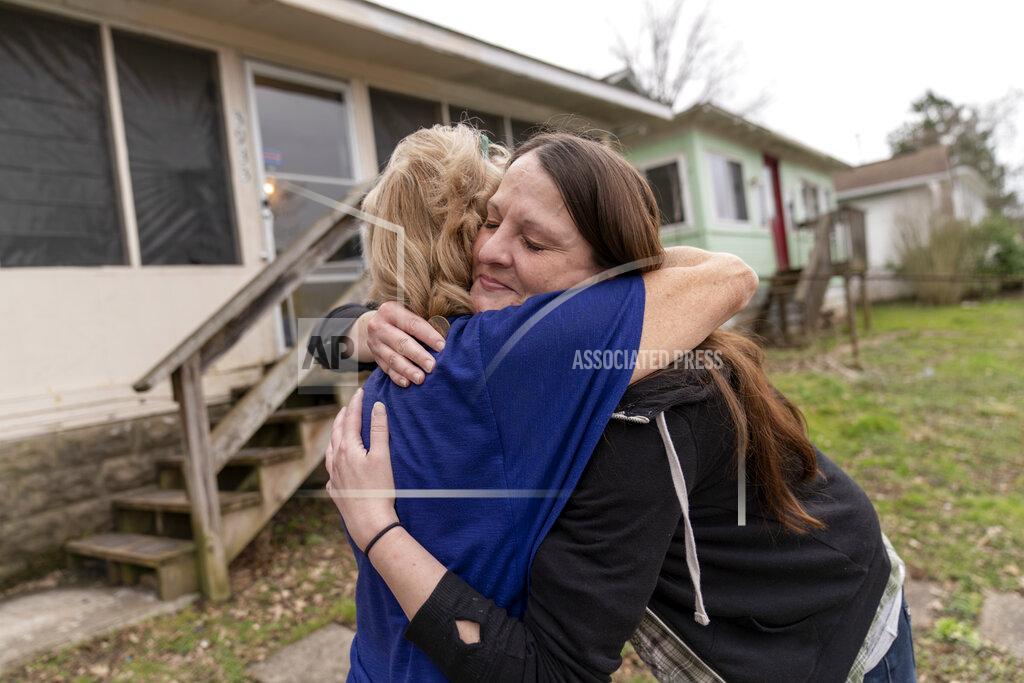 David Goldman Sarah Kelly, right, is embraced by Sue Howland, with the Quick Response Team, after Howland presented her with a coin marking Kelly's one-year anniversary in recovery, outside her home in Guyandotte, W.Va., Wednesday, March 17, 2021. After struggling with opioid addiction most of her life, Kelly white-knuckled her way through the pandemic. "I didn't know where to stop and pick up the pieces. It felt like the task was too overwhelming to get out of the mess I made," she said. "How do you come back from this?" But she did, and it feels to her like a miracle. (AP Photo/David Goldman)