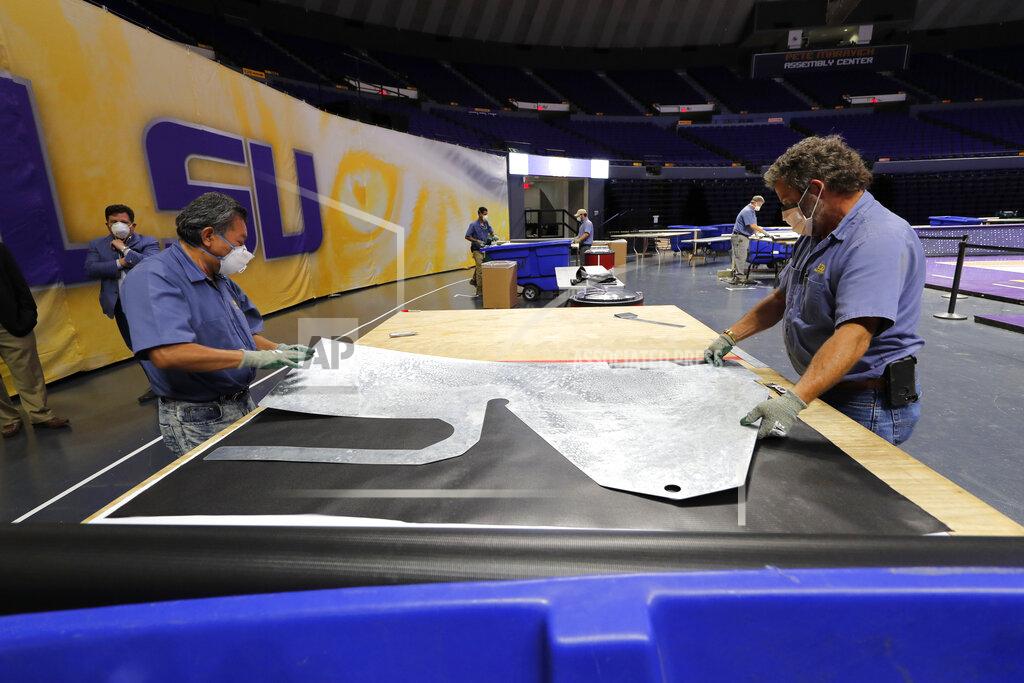 Workers lay a stencil onto material as they manufacture personal protection equipment for hospitals, on the Louisiana State University campus, in response to the coronavirus pandemic, in Baton Rouge, La., Friday, April 17, 2020. (AP Photo/Gerald Herbert)