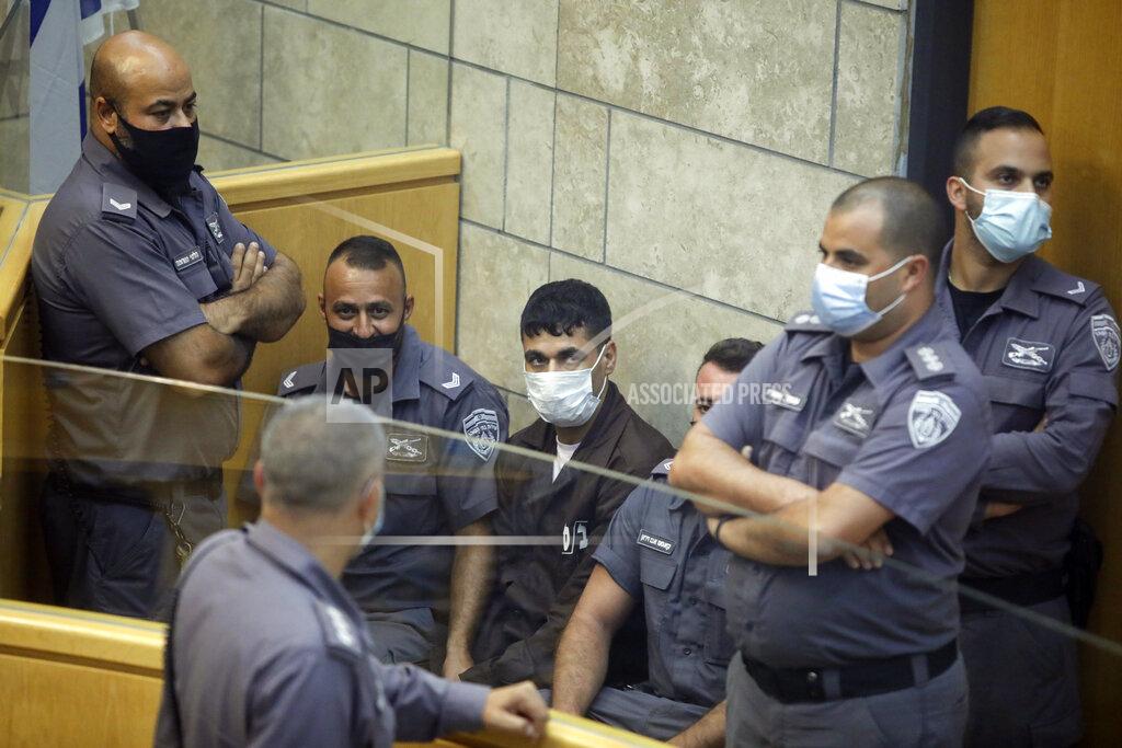 Sebastian Scheiner CORRECTS NAME, Mahmoud Aradeh is surrounded by guards as they stand in a courtroom in Nazareth, Israel, after he and three other Palestinian fugitives were captured on Saturday, Sept. 11, 2021. Israeli police on Saturday said they have arrested four of the six Palestinians who broke out of a maximum-security prison this week including a famed militant leader whose exploits over the years have made him a well-known figure in Israel. (AP Photo/Sebastian Scheiner)