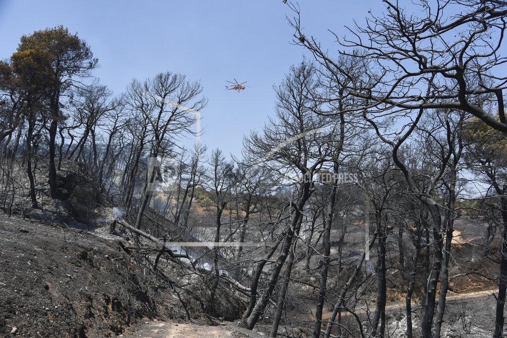 Andreas Alexopoulos A helicopter flies above the burning area near Ziria village, east of Patras, Greece, Sunday, Aug. 1, 2021. A wildfire that broke out Saturday in western Greece forced the evacuation of four villages and people on a beach by the Fire Service, the Coast Guard and private boats, authorities said. (AP Photo/Andreas Alexopoulos)