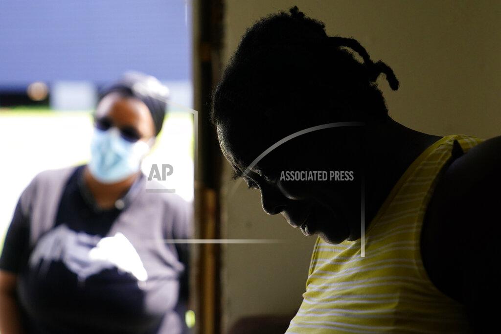 Matt Slocum In the aftermath of Hurricane Ida, Lationa Kemp, 57, pauses while talking with Andreanecia Morris, a housing advocate, Saturday, Sept. 4, 2021, in the Lower Ninth Ward of New Orleans. Full restoration of electricity to some of the hardest-hit areas of Louisiana battered to an unprecedented degree by Hurricane Ida could take until the end of the month, the head of Entergy Louisiana warned Saturday. (AP Photo/Matt Slocum)