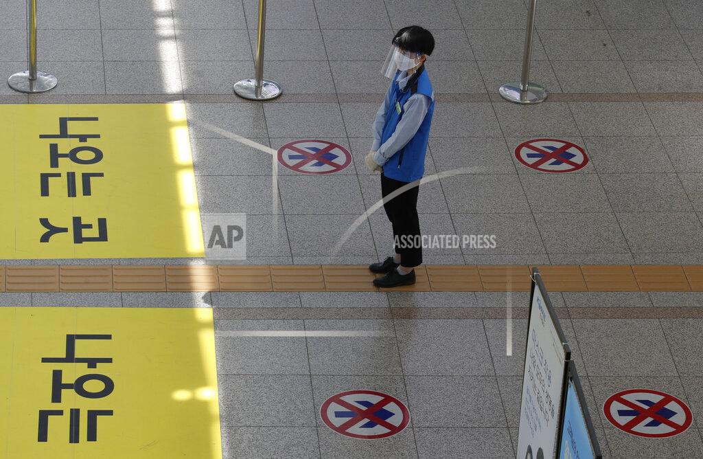 An employee wearing a face mask and face shield stands to guide passengers to maintain a one-way walk flow as a precaution against the coronavirus at the Seoul Railway Station in Seoul, South Korea, Thursday, Sept. 10, 2020. (AP Photo/Lee Jin-man)