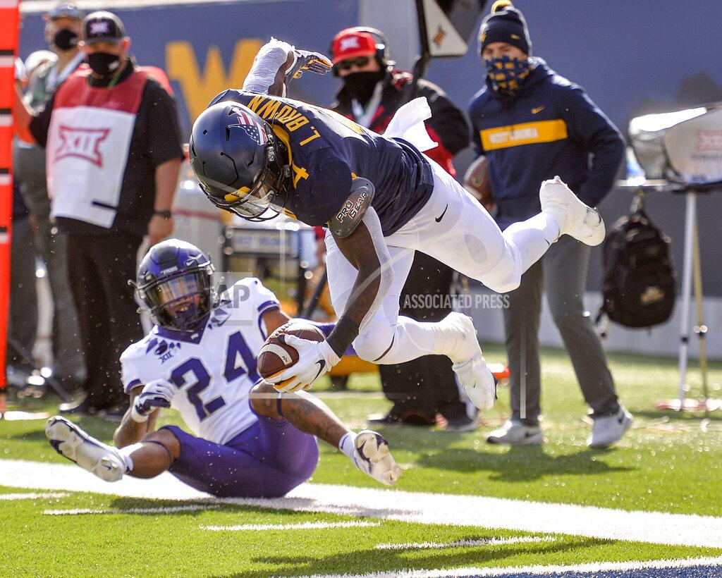 William Wotring West Virginia running back Leddie Brown (4) is tackled by TCU safety Ar'Darius Washington (24) during the first half of an NCAA college football game on Saturday, Nov. 14, 2020, in Morgantown, W.Va. (William Wotring/The Dominion-Post via AP)