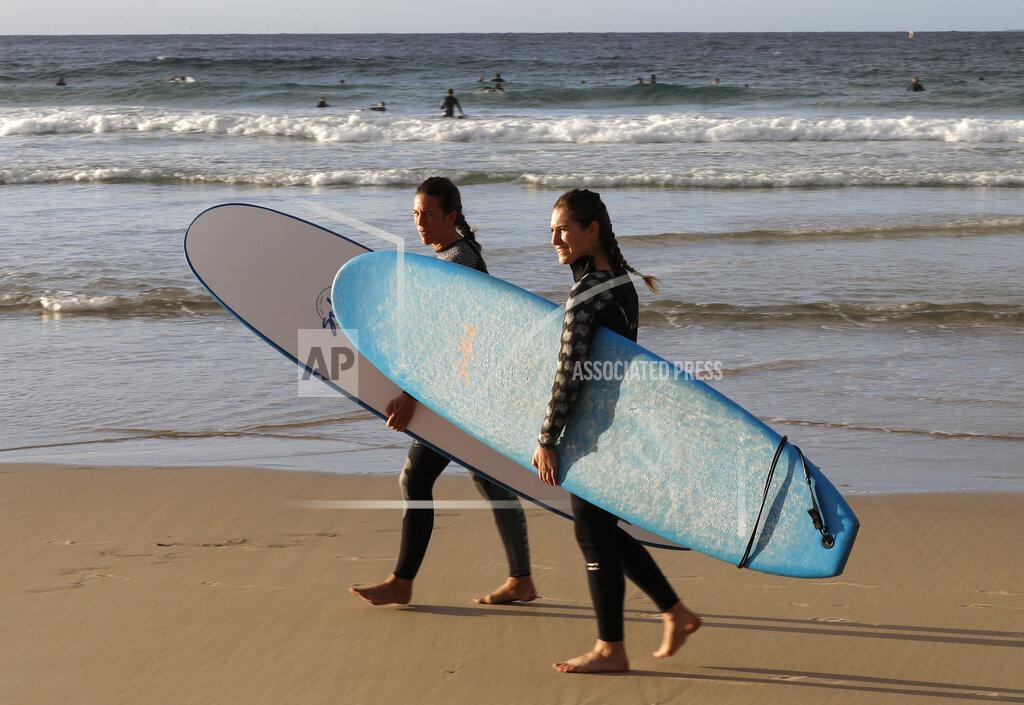 Rick Rycroft Surfers prepare to enter the water at Bondi Beach in Sydney, Tuesday, April 28, 2020, as coronavirus pandemic restrictions are eased. The beach is open to swimmers and surfers to exercise only. (AP Photo/Rick Rycroft)
