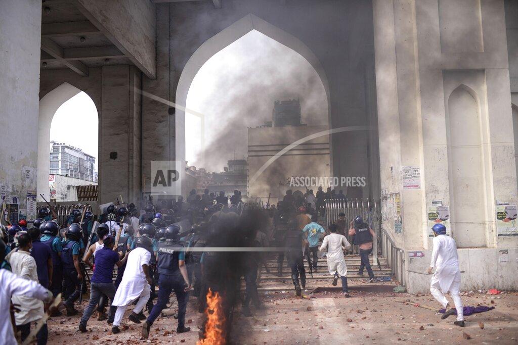 Mahmud Hossain Opu Security officers arrive as two factions of protestors clash after Friday prayers at Baitul Mokarram mosque in Dhaka, Bangladesh, Friday, March 26, 2021. Witnesses said violent clashes broke out after one faction of protesters began waving their shoes as a sign of disrespect to Indian Prime Minister Narendra Modi, and another group tried to stop them. Local media said the protesters who tried to stop the shoe-waving are aligned with the ruling Awami League party. The party criticized the other protest faction for attempting to create chaos in the country during Modi’s visit. (AP Photo/Mahmud Hossain Opu)