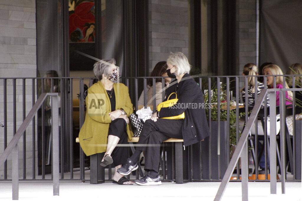 Gillian Flaccus Two women wearing masks wait to be seated at a restaurant in Lake Oswego, Ore., on Friday, May 21, 2021. As the federal government and many states ease rules around mask-wearing and business occupancy, some blue states like Oregon and Washington are still holding on to some longtime coronavirus restrictions. (AP Photo/Gillian Flaccus)