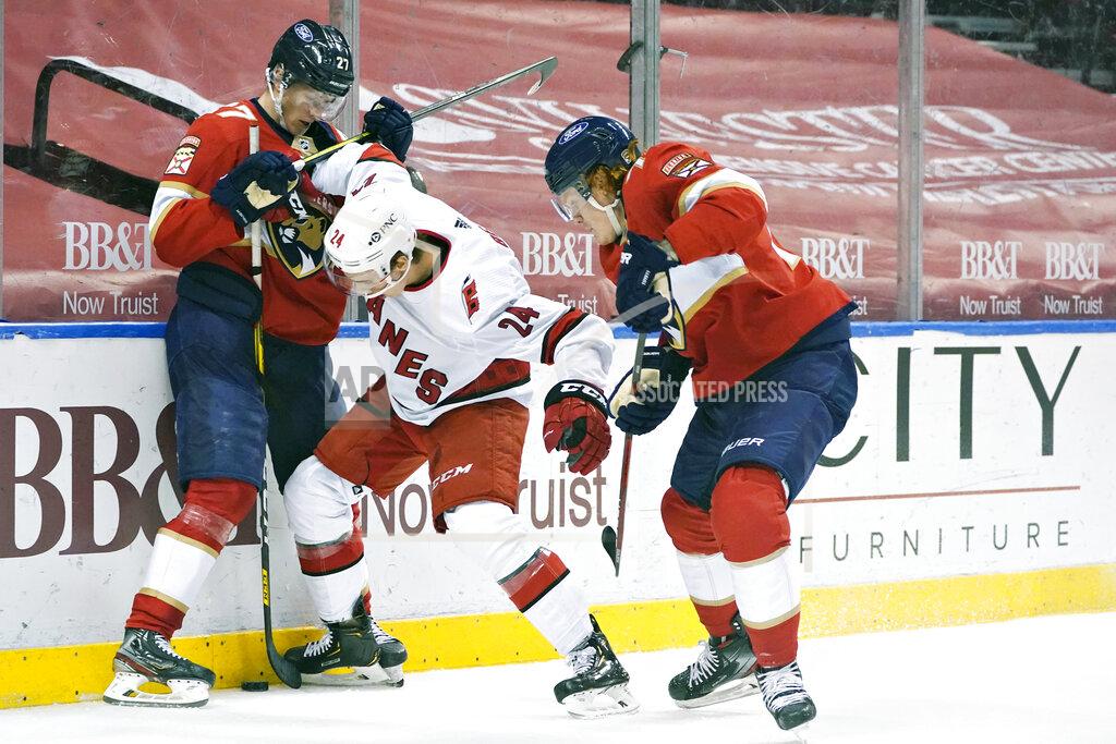 Wilfredo Lee Florida Panthers center Eetu Luostarinen (27) and right wing Owen Tippett, right, battle for the puck with Carolina Hurricanes defenseman Jake Bean (24) during the second period of an NHL hockey game, Monday, March 1, 2021, in Sunrise, Fla. (AP Photo/Wilfredo Lee)