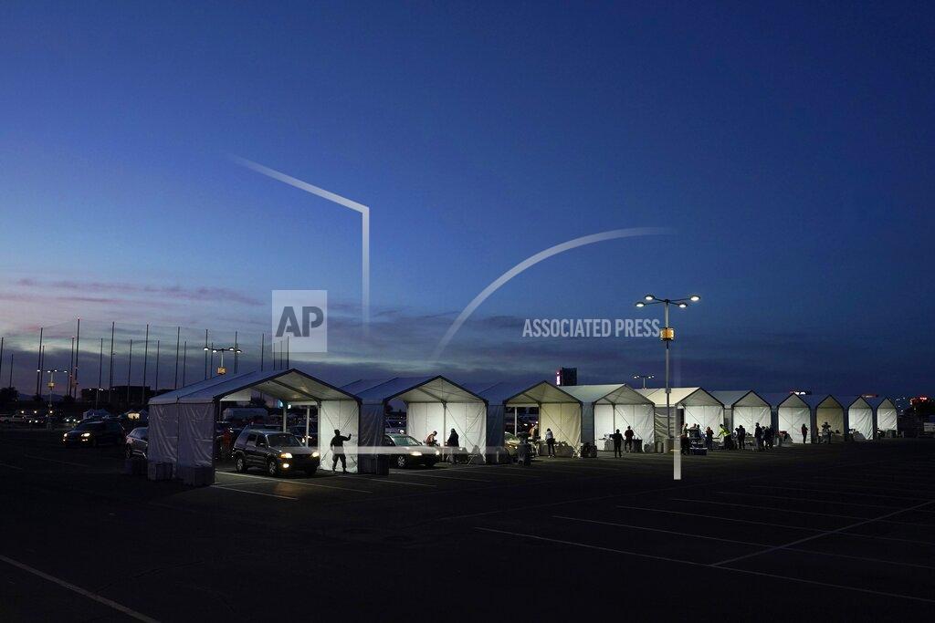 Ross D. Franklin FILE - In this Jan. 12, 2021, file photo, several tents are set up so people who have registered can get their COVID-19 vaccinations as they drive-thru the parking lot of the State Farm Stadium in Glendale, Ariz. Just over 1 million Arizonans are now fully vaccinated against COVID-19, state officials announced Tuesday, March 16, 2021. That represents just under 14% of the state's estimated population of nearly 7.3 million, or about one of every seven Arizonans. (AP Photo/Ross D. Franklin, File)