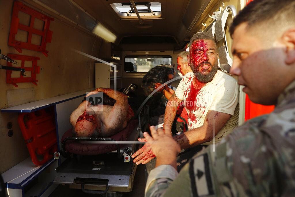 Hussein Malla A Lebanese soldier, right, checks injured men who sit inside an umbulance at the explosion scene that hit the seaport of Beirut, Lebanon, Tuesday, Aug. 4, 2020. Massive explosions rocked downtown Beirut on Tuesday, flattening much of the port, damaging buildings and blowing out windows and doors as a giant mushroom cloud rose above the capital. (AP Photo/Hussein Malla)