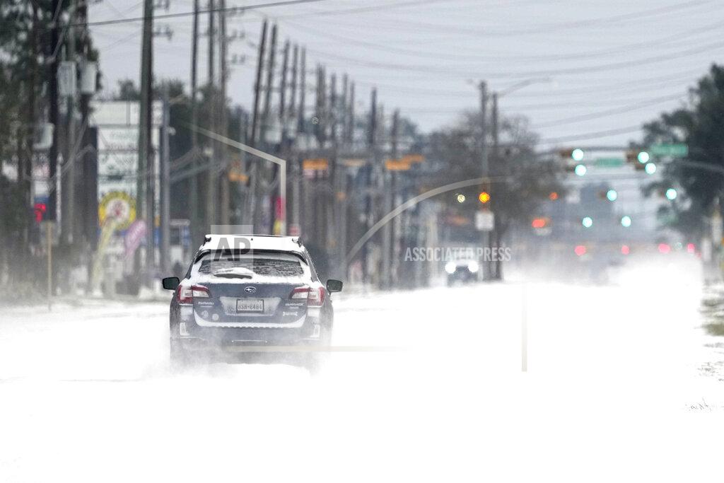 David J. Phillip Vehicles drive on snow and sleet covered roads Monday, Feb. 15, 2021, in Spring, Texas. A winter storm dropping snow and ice sent temperatures plunging across the southern Plains, prompting a power emergency in Texas a day after conditions canceled flights and impacted traffic across large swaths of the U.S. (AP Photo/David J. Phillip)