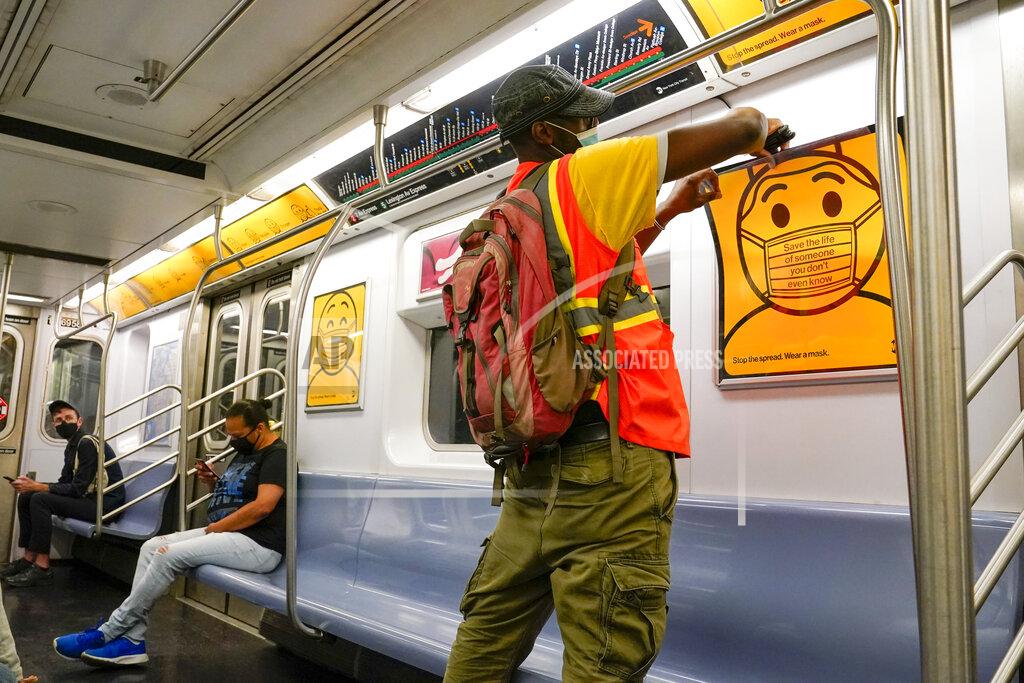 Mary Altaffer An MTA employee replaces posters reminding commuters to wear face masks in a subway car, Monday, Sept. 14, 2020, in the Brooklyn borough of New York. The Metropolitan Transportation Authority announced a new public service campaign to encourage mask usage as well as a new $50 fine policy for those who refuse to wear face coverings on subways, buses and commuter railroads. (AP Photo/Mary Altaffer)
