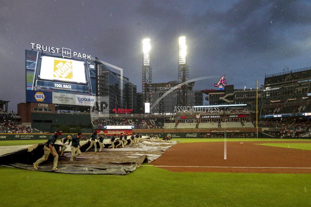 Butch Dill Grounds crew pull out the tarp as rain falls during the fifth inning of a baseball game between the Atlanta Braves and the St. Louis Cardinals Monday, July 4, 2022, in Atlanta. (AP Photo/Butch Dill)