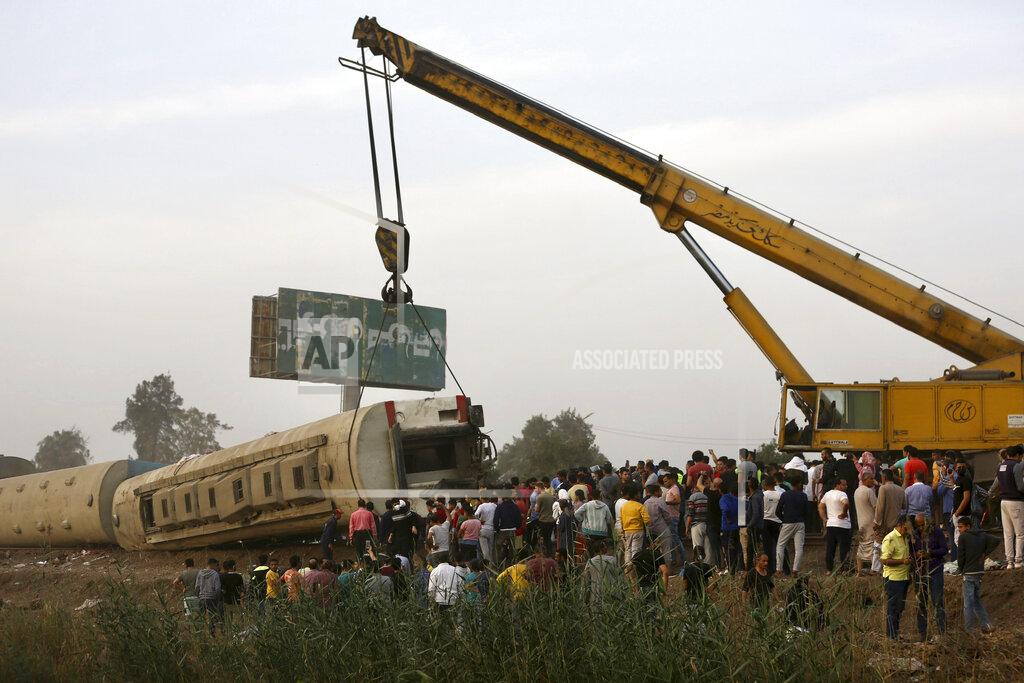 Fadel Dawood A crane is used to lift a part of a passenger train that derailed injuring some 100 people, near Banha, Qalyubia province, Egypt, Sunday, April 18, 2021. At least eight train wagons ran off the railway, the provincial governor's office said in a statement. (AP Photo/Fadel Dawood)