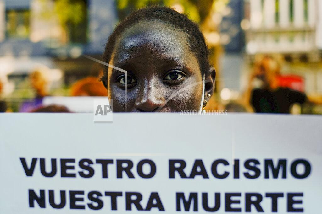 Alvaro Barrientos A woman holds up a banner that reads: "Your Racism, Our Dead", during one of many protests across Spain amid for the investigation over the deaths of at least 23 people at the border between the Spanish enclave of Melilla and Morocco, in Pamplona, northern Spain, Friday, July 1, 2022. (AP Photo/Alvaro Barrientos)