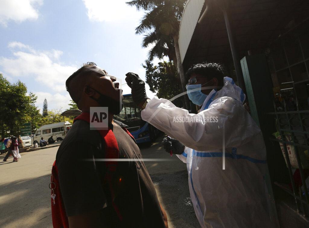 Aijaz Rahi A health worker collects mouth swab of a traveler to test for COVID-19 outside a train station in Bengaluru, India, Monday, Feb. 22, 2021. Cases of COVID-19 are increasing in some parts of India after months of a steady nationwide decline, prompting authorities to impose lockdowns and other virus restrictions. (AP Photo/Aijaz Rahi)