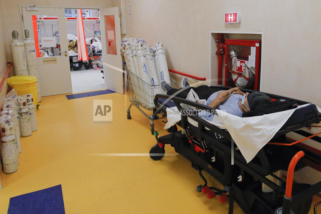 Andreea Alexandru A man lies on a bed in a corridor of the emergency room, turned into a CODIV-19 unit due the high number of cases, at the Bagdasar-Arseni hospital in Bucharest, Romania, Tuesday, Oct. 12, 2021. Romania reported on Tuesday nearly 17,000 new COVID-19 infections and 442 deaths, the highest number of coronavirus infections and deaths in a day since the pandemic started, as the nation's health care system struggles to cope with an acute surge of new cases.(AP Photo/Andreea Alexandru)