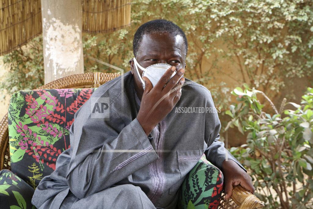 In this photo taken Tuesday, March 24, 2020, Amado Compaore sits outside his house days after his wife Rose Marie Compaore died from the new coronavirus, in Ouagadougou, Burkina Faso. Burkina Faso is one of Africa's nations hardest hit by the coronavirus with one of the highest number of fatalities in sub-Saharan Africa. (AP Photo/Sam Mednick)