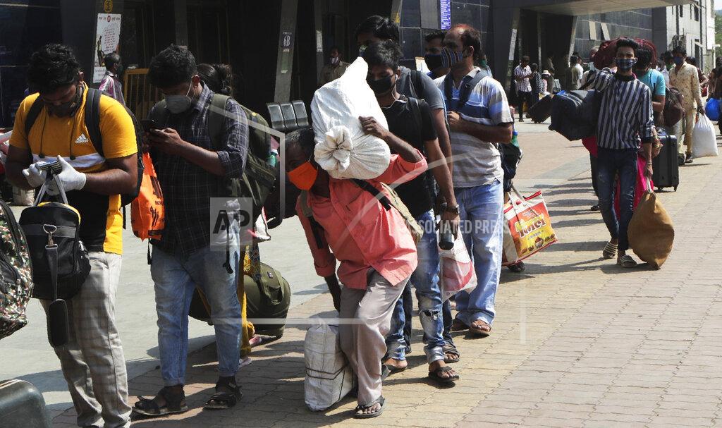 Rajanish Kakade People wearing masks as a precaution against the coronavirus walk to board trains at Lokmanya Tilak Terminus in Mumbai, India, Friday, April 16, 2021. Migrant workers are swarming rail stations in India's financial capital Mumbai to go to their home villages as virus-control measures dry up work in the hard-hit region. The government of Maharashtra state imposed lockdown-like curbs on Wednesday for 15 days to check the spread of the virus. It closed most industries, businesses and public places and limited the movement of people, but didn’t stop the bus, train and air services. An exodus ensued, with panicked day laborers hauling backpacks onto overcrowded trains leaving Mumbai, travel that raises fears of infections spreading in rural areas. (AP Photo/Rajanish Kakade)