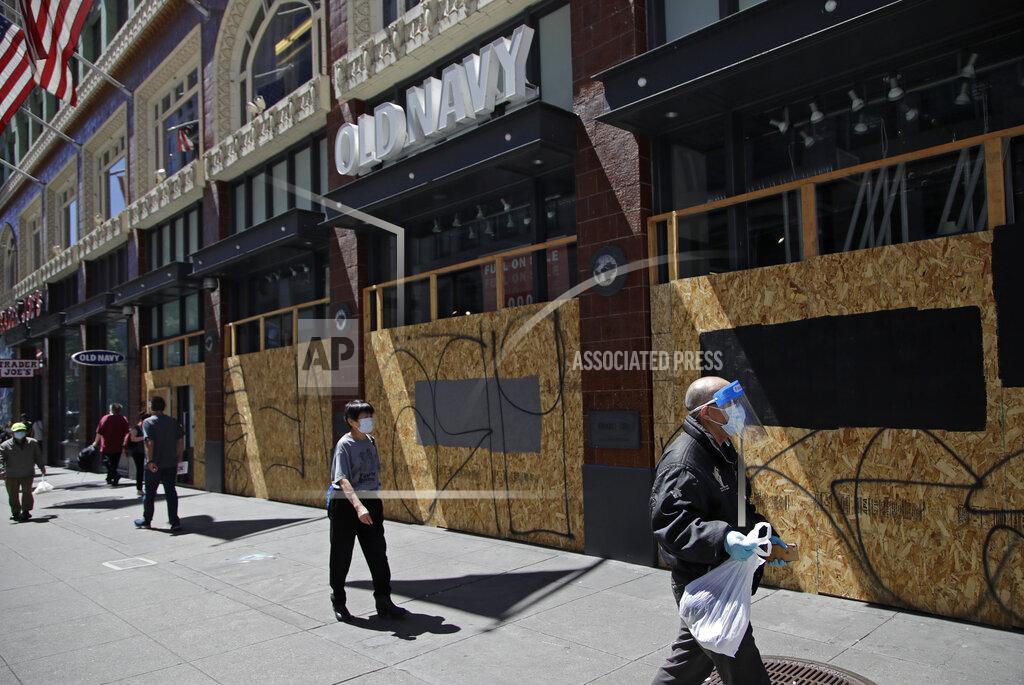 Ben Margot Masked people walk past a boarded up Old Navy clothing store on Wednesday, May 27, 2020, in San Francisco. While much of California moves swiftly to reopen things like hair salons under Gov. Gavin Newsom's guidance, the San Francisco Bay Area is continuing to keep the brakes on. Some health officials are questioning whether the state is taking enough time to assess the effects of reopening things like stores before jumping ahead to broader re-openings, risking a surge in infections. (AP Photo/Ben Margot)
