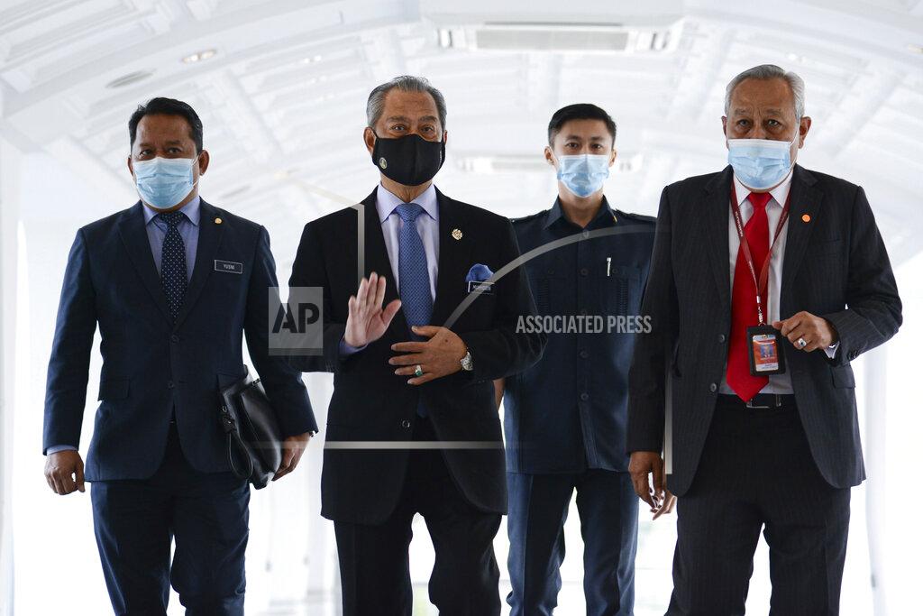 Famer Roheni In this photo release by Malaysia Information Ministry, Malaysia's Prime Minister Muhyiddin Yassin, second left, waves as he arrives for a session of the lower house of parliament, in Kuala Lumpur, Malaysia Thursday, Nov. 26, 2020. Malaysia's Parliament Thursday approved the government's proposed 2021 budget, throwing a political lifeline to embattled Prime Minister Muhyiddin Yassin amid strong resistance to his nine-month-old leadership. (Famer Roheni/Malaysia's Department of Information via AP)