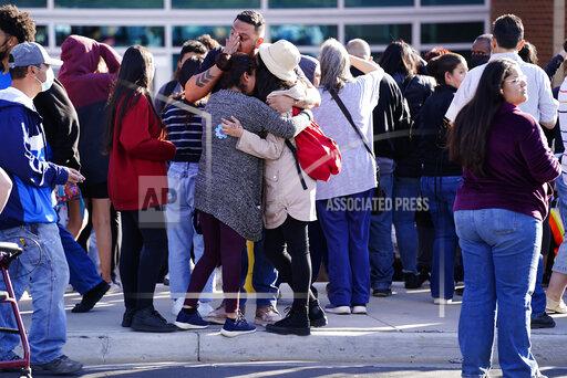 FILE - Edgar James, front center, battles with tears as he hugs his daughter, Mia, front right, and his wife, Olga Aguirre, front left, as they are reunited outside Hinkley High School in Aurora, Colo., on Friday, Nov. 19, 2021. A string of shootings involving teenagers has placed renewed attention on a long-running problem of gun violence and gangs in Aurora just outside Denver. Activists and officials say easy access to guns is contributing to the problem in Colorado's third largest city. (Philip B. Poston/Sentinel Colorado via AP,File)