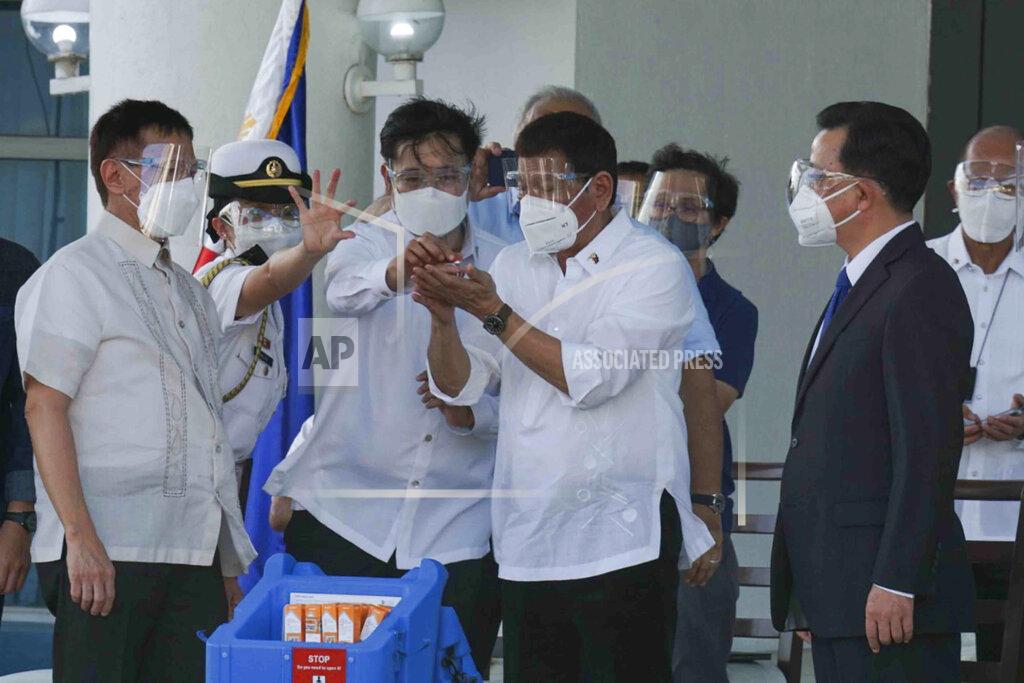 Uncredited In this photo provided by the Presidential Communications Operations Office-Office of the Global Media Public Affairs, Philippine President Rodrigo Duterte, center, looks at a vial containing the Sinovac vaccine from China as it arrives at the Villamor Air Base in Manila, Philippines on Sunday Feb. 28, 2021. The Philippines is due to receive its first batch of COVID-19 vaccine Sunday, among the last in Southeast Asia to secure the critical doses despite having the second-highest number of coronavirus infections and deaths in the hard-hit region. (PCOO-OGMPA via AP)