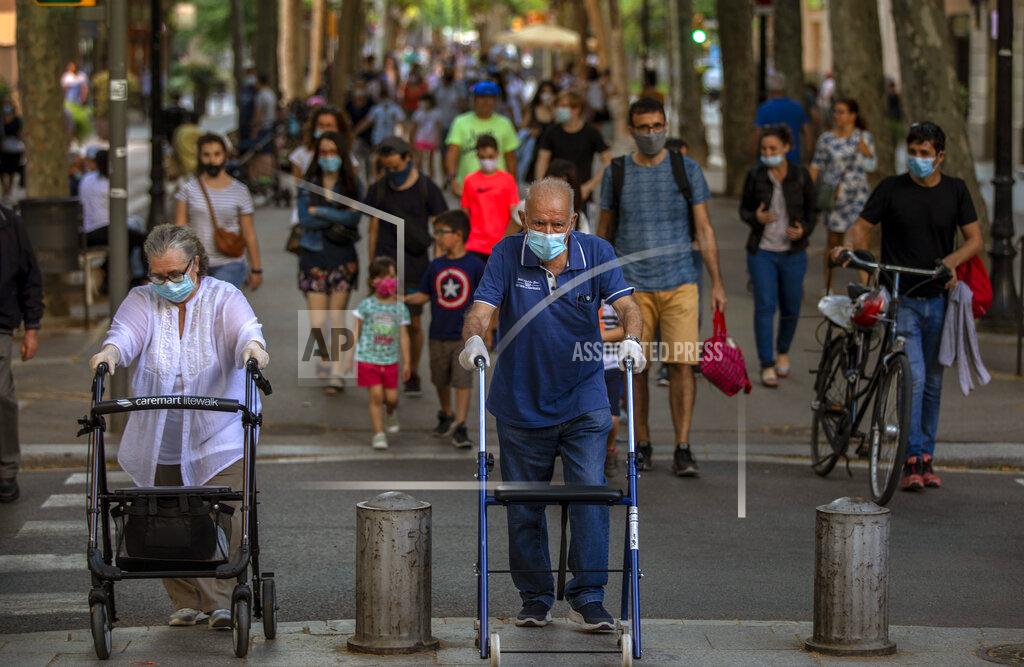 Emilio Morenatti People walk on a street in Barcelona on Monday, May 25, 2020. Roughly half of the population, including residents in the biggest cities of Madrid and Barcelona, are entering phase 1 on Monday, which allows social gatherings in limited numbers, restaurant and bar service with outdoor sitting and some cultural and sports activities. (AP Photo/Emilio Morenatti)